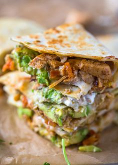 a stack of food sitting on top of a piece of wax paper next to chips