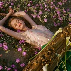 a woman laying on the ground in front of flowers with her arms behind her head