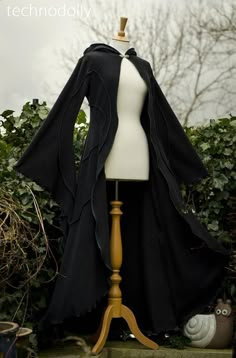 ~ Haunted Hawtin Cloak ~ The floor length Haunted Hawtin Cloak is a simple & beautiful design. Made using soft fleece fabric with elegant trim detail to create a delicate flowing line of colour & form. It is floor length with large medieval flared sleeves, a open front with a single clasp fastening at the throat & pixie hood.This coat has a Norwegian Clasps fastening at the throat in either silver or gold - please let me know which colour you would like when placing your order :) As we are all u Witch Cloak Aesthetic, Cloak Designs, Witch Robes, Black Cloak With Hood, Cloak With Sleeves, Cloaks Hooded, Witch Coat, Dark Cloak, Medieval Coat