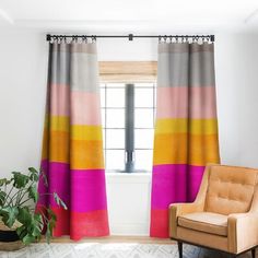 a living room with a chair, window and rug in front of the curtains that are multicolored