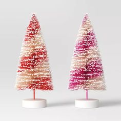 two small christmas trees on white bases with red, pink and white frosted tops