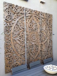 an intricately carved wood panel on the wall above a dining room table with blue chairs