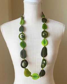 The Trinity necklace is a natural beauty. This long and lightweight necklace features an artful collection of seeds in different shapes and  in different shades of green: olive green, pear green and and pine green. This stunning necklace is the perfect addition to highlight solids and prints. Pair it with our tagua earrings to complete the look.  Thanks to the natural characteristics you can be sure yours is unique. Tagua, also called the vegetable ivory is the seed of a palm tree that grows in the tropical rainforests of several South American countries including Colombia, and Ecuador. Adjustable Teardrop Green Necklace, Green Adjustable Teardrop Necklaces, Artisan Long Green Necklace, Adjustable Nature-inspired Necklaces With Natural Variations, Nature-inspired Green Necklaces With Natural Stones, Green Natural Stones Nature-inspired Necklace, Adjustable Green Beaded Necklace In Nature-inspired Style, Adjustable Green Beaded Necklace With Nature-inspired Style, Nature-inspired Green Beaded Necklace With Round Beads