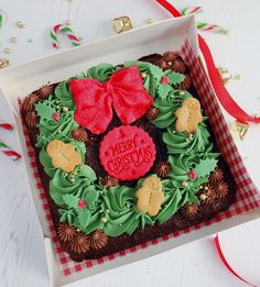 a christmas cookie decorated with green icing and red bows in a box on a table