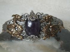 This beautiful silver plated filigree cuff bracelet has antique brass dragons, silver plated accents and an amethyst setting. Adjustable. Silver Fantasy Jewelry For Formal Occasions, Medieval Handmade Wedding Jewelry, Fantasy Amethyst Jewelry For Gifts, Fantasy Style Amethyst Jewelry For Gifts, Fantasy Bronze Metal Jewelry, Elegant Hand Cast Antique Silver Jewelry, Antique Hand Cast Jewelry For Formal Occasions, Formal Antique Hand Cast Jewelry, Medieval Style Silver Jewelry With Intricate Design