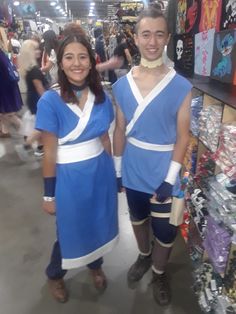 two people dressed in costumes standing next to each other at a store with lots of items on the shelves