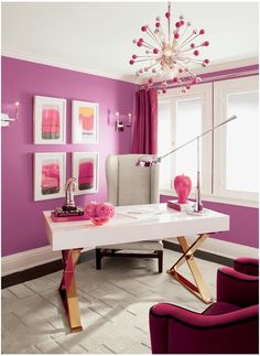 a living room with purple walls and pictures on the wall above the table, along with two red chairs