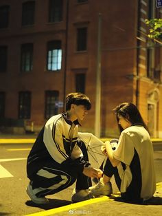 a man and woman sitting on the ground next to each other