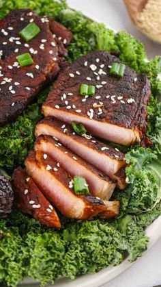 some meat and greens on a plate with sesame seed sprinkled around the edges