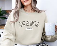 Wrap yourself in warm, cozy vibes with this collegiate varsity letter "School Secretary" sweatshirt, perfect for any school secretary, principal secretary, school receptionist or school bookkeeper. Designed to keep you comfortable while showing off your school spirit, this sweatshirt is a must-have for every dedicated school secretary.  It makes a great Christmas gift for sister, birthday gift for best friend, or an anniversary gift for wife. This cozy sweatshirt is made from a soft, midweight c Trendy Sweatshirt For School In Fall, Trendy Fall Sweatshirt For School, Collegiate Letter Print Sweatshirt For School, Collegiate Style Sweatshirt With Letter Print For School, Collegiate Sweatshirt With Letter Print For School, College Style Letter Print Sweatshirt For School, Sporty Letter Print Sweatshirt For School, Sporty School Sweatshirt With Letter Print, Varsity Graphic Print Sweatshirt For School