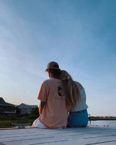 two people sitting on a dock looking at the water