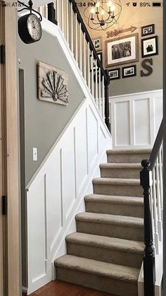 stairs leading up to the second floor with pictures on the wall and clock above them