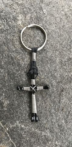 a metal keychain with a cross on it sitting on top of a rock