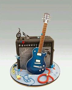 a blue guitar and amp cake on top of a plate with decorations around the edges