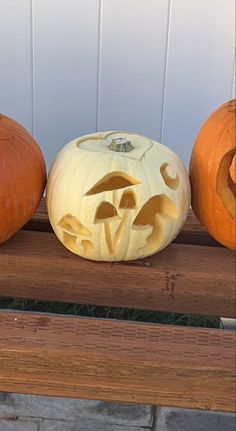 three carved pumpkins sitting on top of a wooden bench