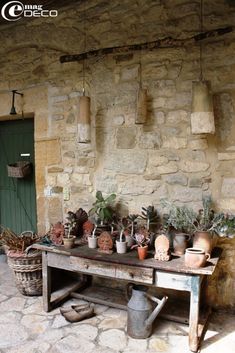 an old table with potted plants on it in front of a stone wall and door