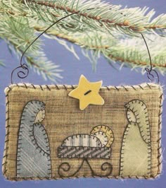 a christmas ornament hanging on a tree branch with a star and nativity scene