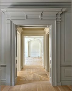 an empty hallway with white walls and wood floors