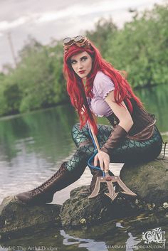 a woman with red hair is sitting on some rocks