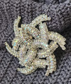 What a substantial piece of sparkling jewelry, perfect for holiday parties!  This large dimensional rhinestone brooch is an amazing, professionally crafted piece with layers of faceted, sparkling aurora borealis rhinestones sandwiched between rows of grayish taupe colored rhinestones and a larger faceted grayish taupe rhinestone in the center.  All rhinestones are prong set, the pin is in great shape and the safety clasp is in excellent working condition. The brooch measures 2 3/4 inches in diameter and 5/8 of an inch in depth, not including the pin.   Unfortunately this beautiful pin is unmarked.  This brooch reminds me of an octopus or a pinwheel gone crazy Very good used uncleaned vintage condition.  Please take note the size given in the description, as photos can often appear larger t Crystal Brooches With Sparkling Stones For Party, Party Crystal Brooches With Sparkling Stones, Party Brooches With Sparkling Crystal Stones, Glamorous Rhinestones Brooches For Party, Sparkle Jewelry, Taupe Color, Hollywood Glam, Fashion Costume, Rhinestone Brooches