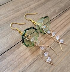 two pairs of earrings with green glass beads and gold earwires on a wooden surface