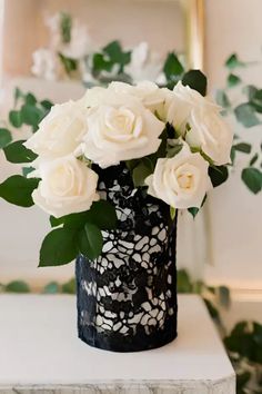 white roses in a black vase on a table