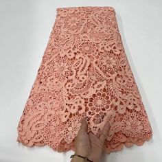 someone is cutting out the edge of a pink lace fabric with scissors and glue on it