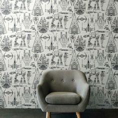 a gray chair sitting in front of a wall with black and white designs on it