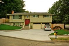 a car parked in front of a house on a street with grass and trees around it