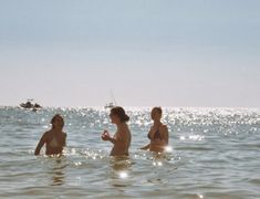 three people in the water with one holding a cell phone and another looking at something