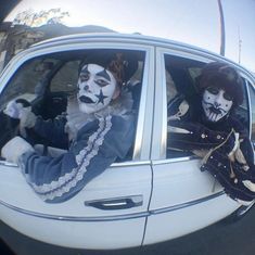 two clowns are sitting in the passenger seat of a car with their faces painted white