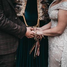 the bride and groom hold hands as they stand next to each other in their wedding attire