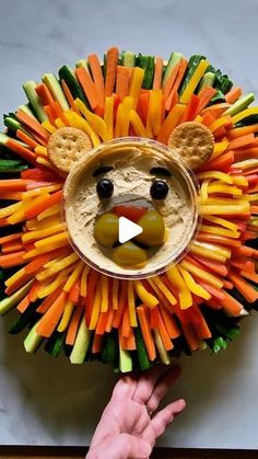 a lion made out of veggies and crackers with a hand holding it