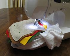 a white sewing machine on top of a wooden table next to a piece of cloth