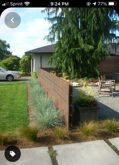 a wooden fence in the middle of a yard with flowers and plants growing on it