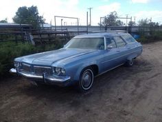 an old blue car is parked in the dirt