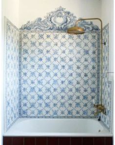 a bathroom with blue and white tiles on the wall, shower head and faucet