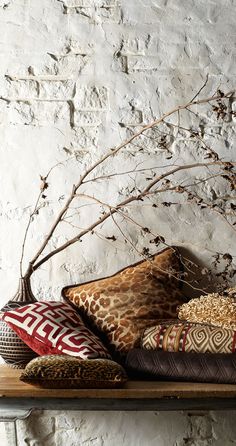 an animal print pillow on a wooden shelf next to a vase with flowers in it