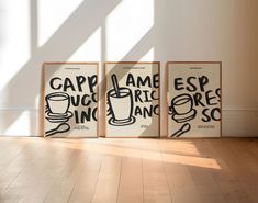 three black and white posters on the wall in an empty room with wood flooring