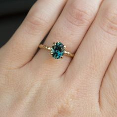 a woman's hand with a ring on it and a blue stone in the middle