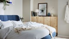 an unmade bed with white sheets and blue headboard