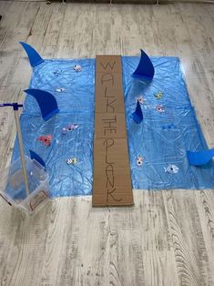 a cardboard sign sitting on top of a blue tarp covered floor next to an umbrella