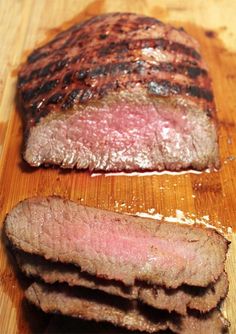 two pieces of steak sitting on top of a wooden cutting board next to each other