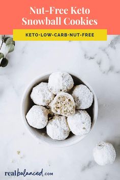 a white bowl filled with snowball cookies on top of a marble counter next to eucalyptus branches