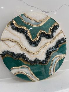 a green and white plate with gold trimmings sitting on a marble counter top