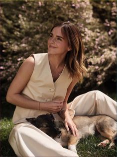 a woman sitting in the grass with her dog