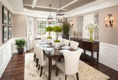 a dining room table with white chairs and plates on it