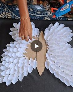 a woman is making a paper flower decoration with scissors and glue on the top of it