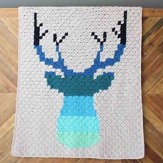 a crocheted deer head on a white background with blue and green yarns