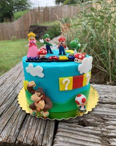 a cake decorated with mario and luigi's family on top of a wooden table